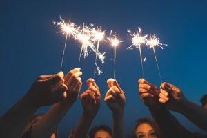 Many hands holding up sparklers representing Ignite Faith Niagara Leadership Development