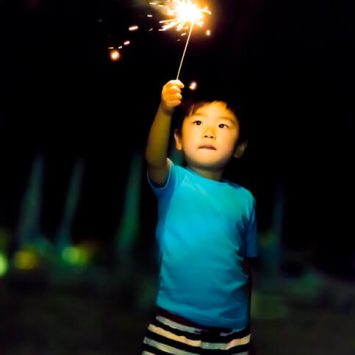 Young Asian boy holding a sparkler representing Ignite Faith Niagara